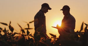 2 farmers talk in a field. 