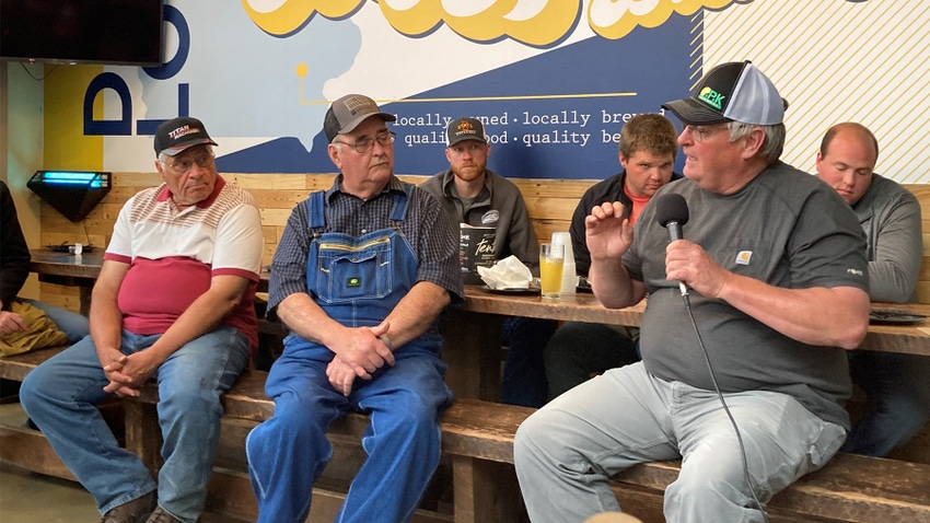 Men at picnic table at brewpub listening to speaker