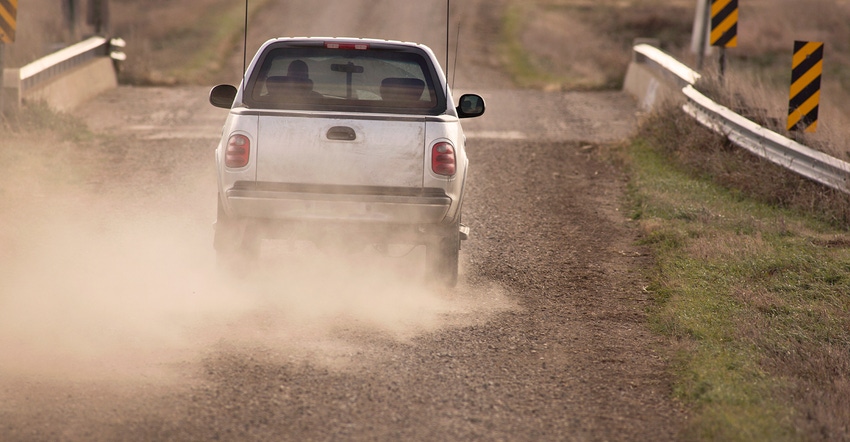 pickup driving on a dusty rural road