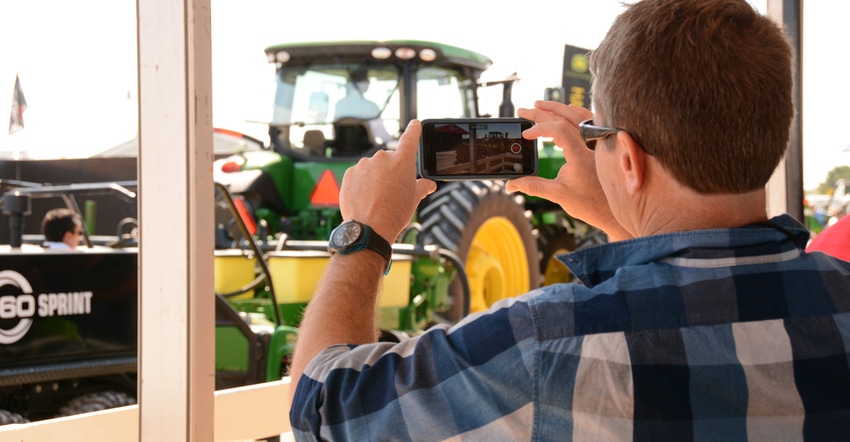 man taking photo of tractor using cellphone