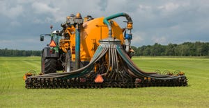 injecting of liquid manure with green tractor and yellow vulture spreader trailer