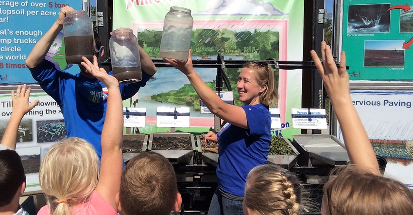 kids at the Conservation Station trailers with instructors holding jars of dirt kids at the Conservation Station trailers with instructors holding jars of dirt