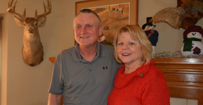 Janet and David olson in living room next to hunting trophies