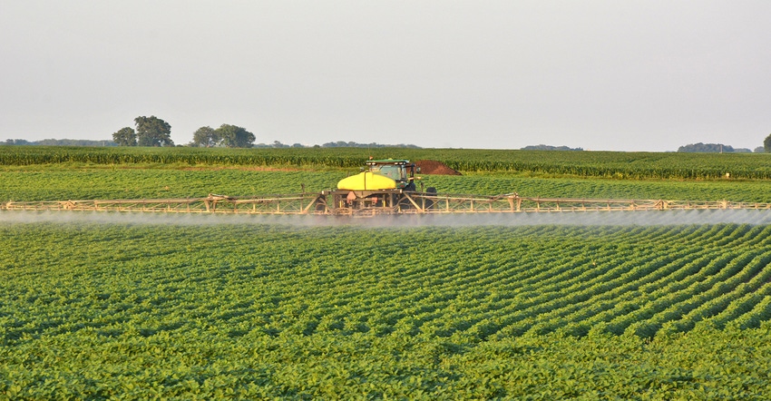 tractor and applicator spraying soybean field