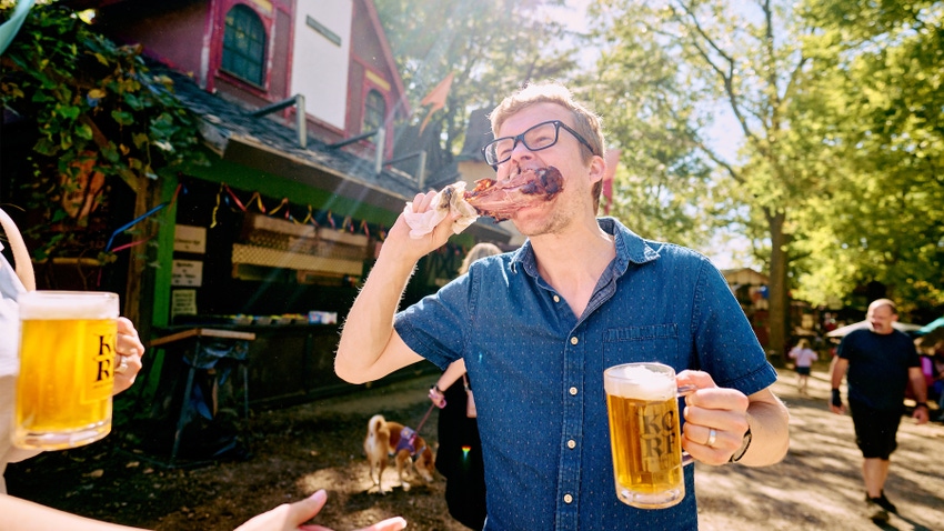 man eating turkey leg and holding a beer