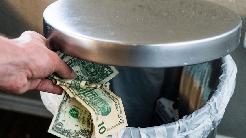 U.S. dollars being tossed in garbage can