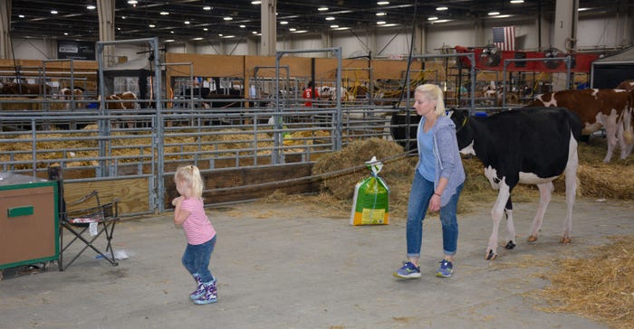 Abigail Dunn helps her mother, Melissa, lead their cow through the exhibitor hall at All-American Dairy Show