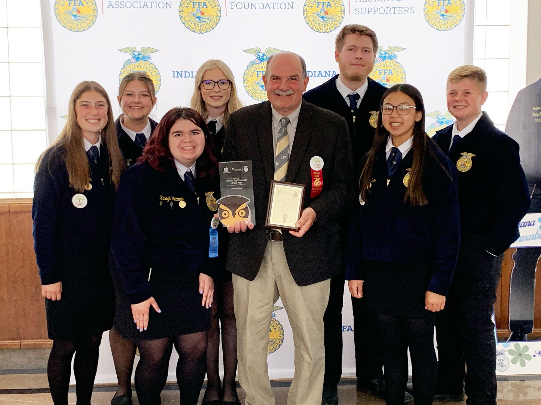 Duane Huge holding two plaques, surrounded by FFA members