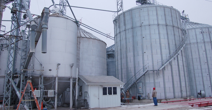 man standing in front of grain bins