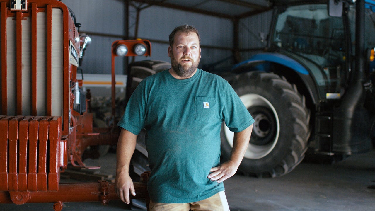 Farmer Jason Russell standing by machinery in machine shed on his Iowa farm.