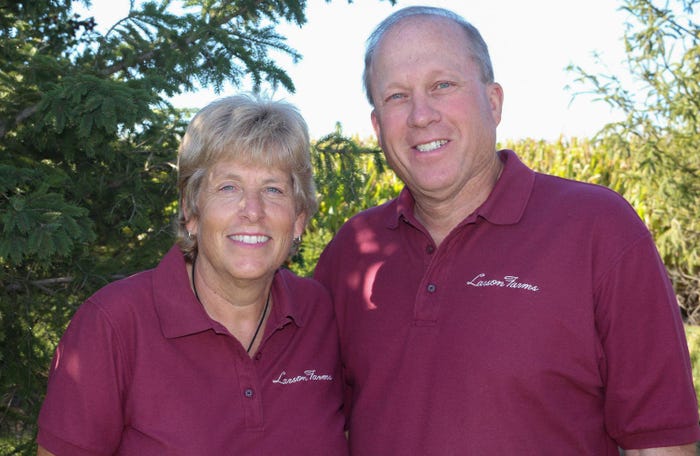 A man and a woman wearing maroon collard shirts stand next to each other as they smile for a photo