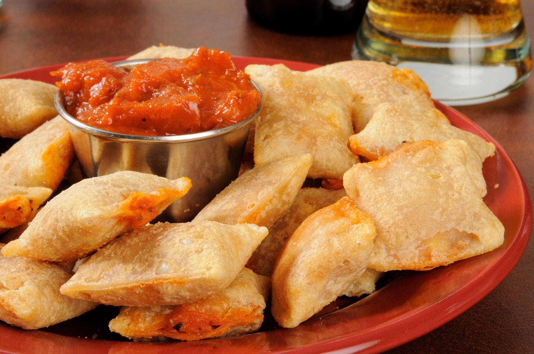 plate of pizza rolls with cup of marinara sauce in the middle