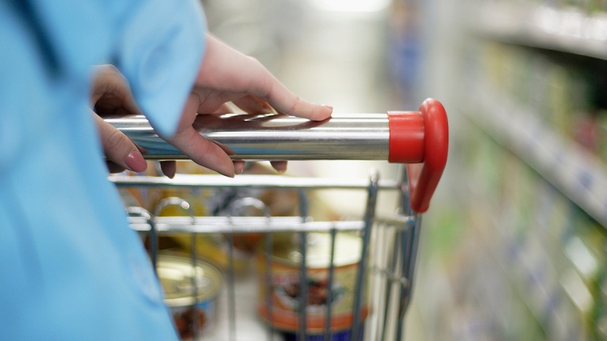 Person pushing grocery cart through food store aisle. Person pushing grocery cart through food store aisle.