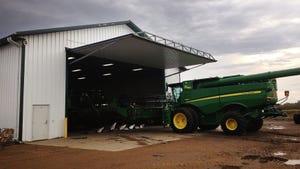 A barn with a hydraulic lift door and a green and yellow tractor