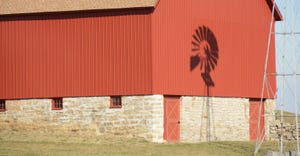 shadow of windmill on side of red barn