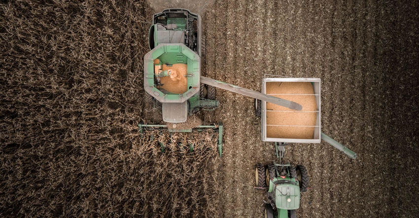 Drone view of combine and tractor harvesting corn field