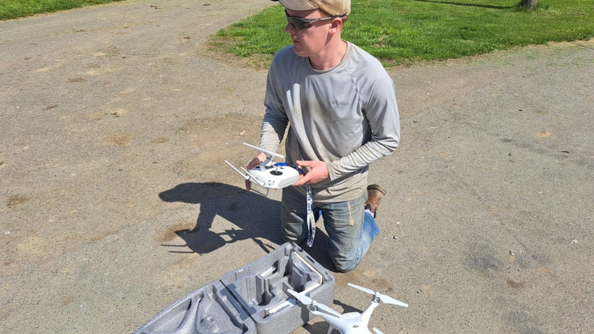 William Thiele kneeling on ground while controlling a DJI Phantom 4 Pro drone
