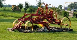 old road grader painted red and yellow and displayed in a yard