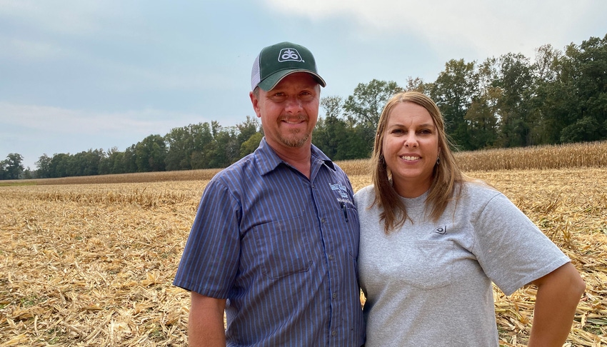 Husband and wife stand in corn field.
