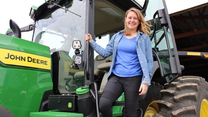 Rachel Stevens standing on a John Deere tractor