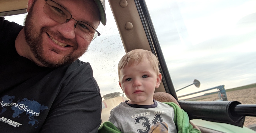 Adam Gittins, with son by his side, collects yield data and other information gathered by precision ag tools in the field.