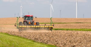Farmer seeding corn next to wind farm