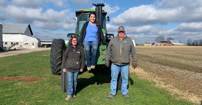 April, Gracie, and Ron Flaspohler pose in front of a family favorite tractor