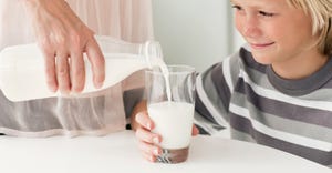 mother pouring milk for son