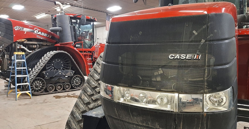 Two tractors in  the shed, one closeup and one in background.