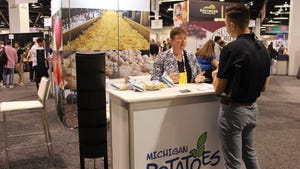 A visitor of the Global Produce and Floral Show speaking with a representative at a potato chip stand