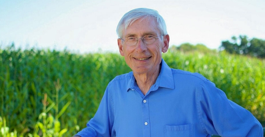 Wisconsin Governor Tony Evers smiling with a crop field in the background