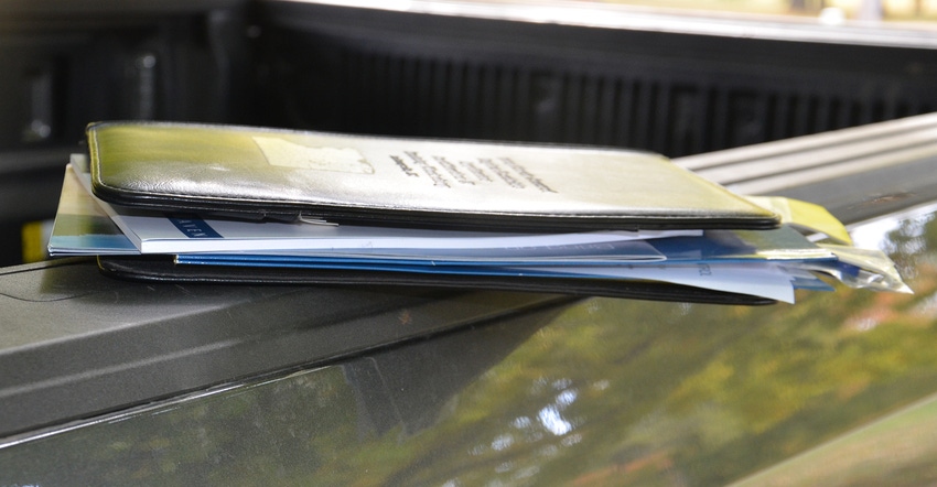 folder full of papers resting on back of truck