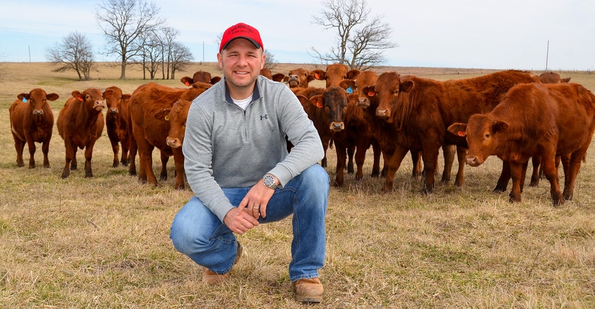 Craig Johnson in the middle of pasture surrounded by beefmaster heifers