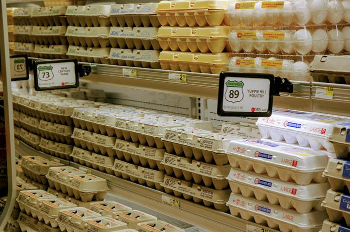 Cartons of eggs stacked in the refrigeration section of a grocery store