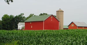 A red barn and silo behind a field
