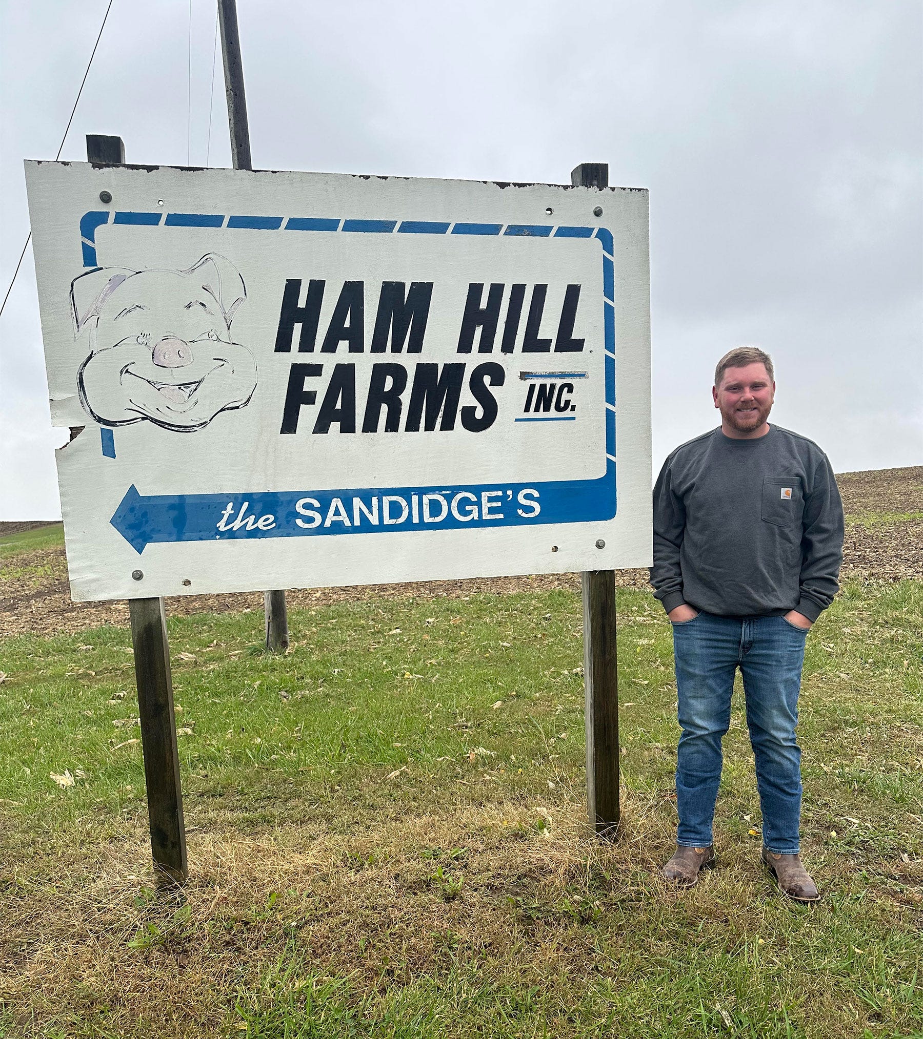 Missouri Farmers Care - Mason Sandidge standing next to a sign for Ham Hill Farms, Inc.