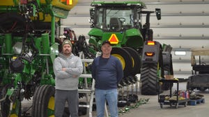 Brandon Christiansen (left) and his father, Rick, of Plainview, Neb. in front of farm equipment in shop