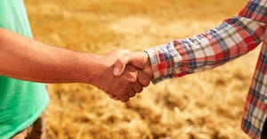 Two farmers shaking hands in a field.