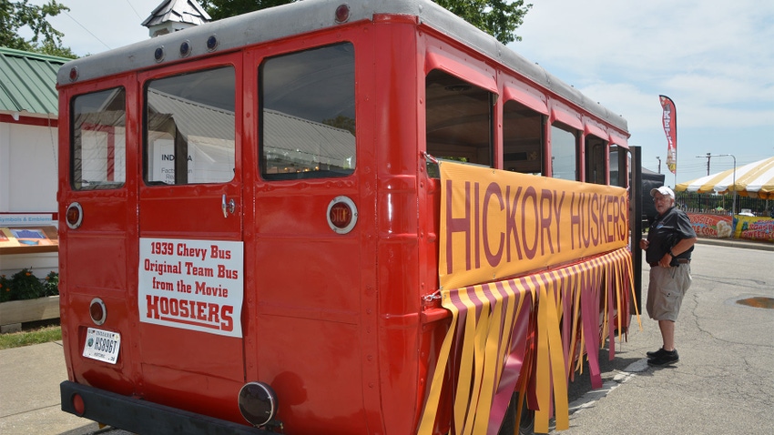An old red school bus decorated with a yellow and red banner