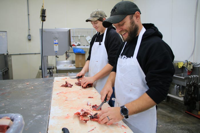 Stephen Vallette and Braxton Warren trim cuts of meat