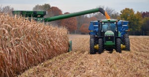 combine harvesting corn and loading grain cart in field