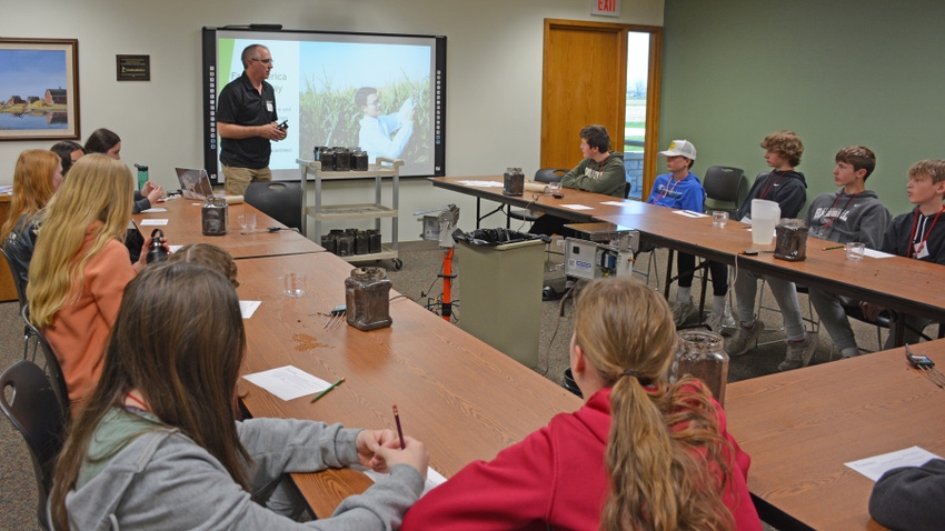 Executive gives presentation to students seated at tables in U shapes