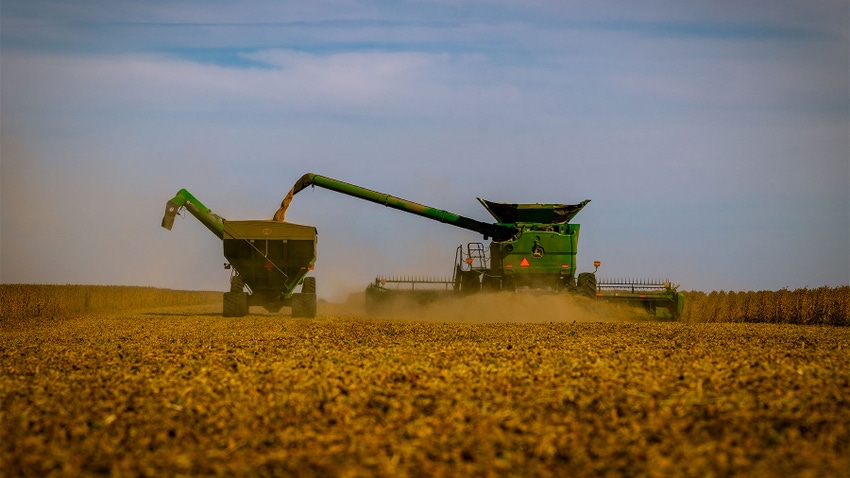 A combine and tractor harvesting a crop