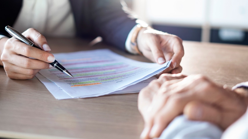 Business adviser pointing at paperwork with pen on desk