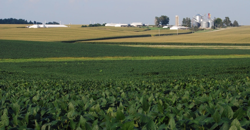 Landscape view of corn and soybean fields with farm buildings on horizon Landscape view of corn and soybean fields with farm buildings on horizon