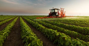 Tractor spraying a field of soybeans