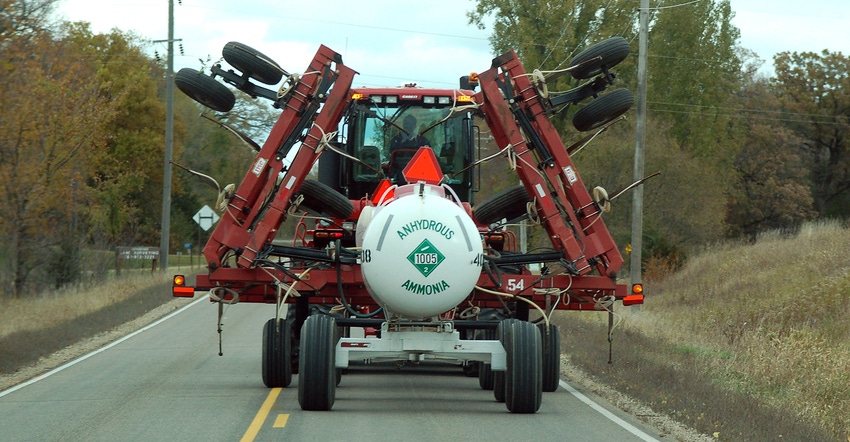 tractor carrying anhydrous ammonia tank driving down rural road