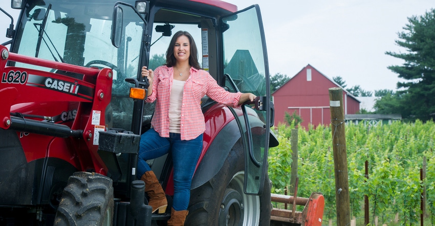 Shelby Watson-Hampton stands on the steps to the cab of her tractor