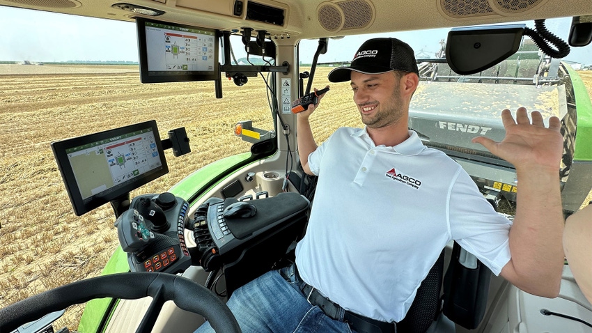 A young man sits in a tractor with his hands in the air