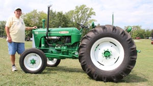Doug Kautzer standing with green 1958 model 550 Oliver tractor
